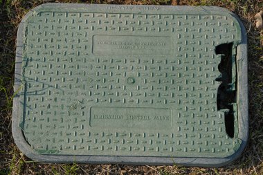 Dubai BAE Aralık 2019 Sulama kontrol kapakçığı için eski kırık bir plastik kutu. Arka planda kuru yeşil, kahverengi çimenler var. Dışarıdaki çimlerin altına otomatik sulama sistemi kurulmuş yeşil valf..