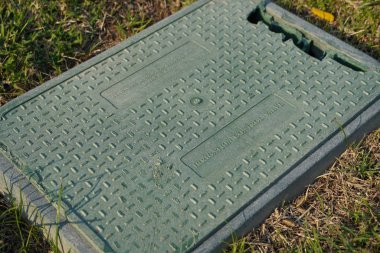 Dubai BAE Aralık 2019 Sulama kontrol kapakçığı için eski kırık bir plastik kutu. Arka planda kuru yeşil, kahverengi çimenler var. Dışarıdaki çimlerin altına otomatik sulama sistemi kurulmuş yeşil valf..