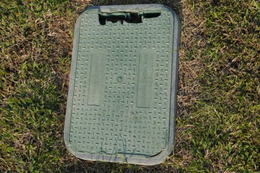 Dubai BAE Aralık 2019 Sulama kontrol kapakçığı için eski kırık bir plastik kutu. Arka planda kuru yeşil, kahverengi çimenler var. Dışarıdaki çimlerin altına otomatik sulama sistemi kurulmuş yeşil valf..