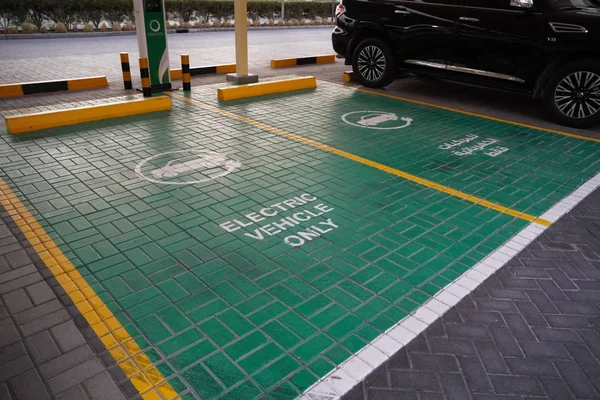 Zielony znak stacji ładowania pojazdów elektrycznych na parkingu. Miejsce parkingowe dla pojazdów elektrycznych. Elektryczna stacja ładowania samochodów. Zjednoczone Emiraty Arabskie grudzień 2019 — Zdjęcie stockowe