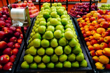 Süpermarkette bir sürü yeşil, turuncu, kırmızı elma kutuları. Elmalar halka açık pazarda satılıyor. Organik yiyecekler mağazada taze elmalar Dubai BAE Aralık 2019