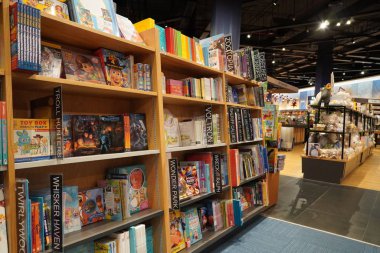 Satılık bir kitapçıda raflara kitap çizip boyayan çocuklar. Kütüphane çocukları kitapları bölümü. Kütüphane 'deki kitaplıkta satılık kitapların çeşitliliği. Süpermarket. Dubai Uae Aralık 2019.