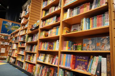 Satılık bir kitapçıda raflara kitap çizip boyayan çocuklar. Kütüphane çocukları kitapları bölümü. Kütüphane 'deki kitaplıkta satılık kitapların çeşitliliği. Süpermarket. Dubai Uae Aralık 2019.