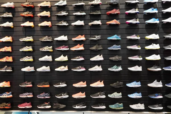 Shop display of a lot of Sports shoes on a wall. A view of a wall of shoes inside the store. Modern new stylish sneakers running shoes for men and women - Dubai UAE December 2019 — Stock Photo, Image