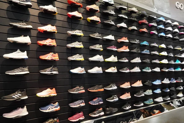 Winkel display van een heleboel sportschoenen op een muur. Een uitzicht op een muur van schoenen in de winkel. Moderne nieuwe stijlvolle sneakers voor dames en heren - Dubai Verenigde Arabische Emiraten december 2019 — Stockfoto