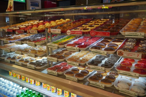 Pastacı Krispy Kreme 'de vitrinde çeşitli lezzetli çörekler sergileniyor. Pastanedeki raflarda çeşitli çörekler var. Şekerleme seçimi. - Dubai Uae Aralık 2019