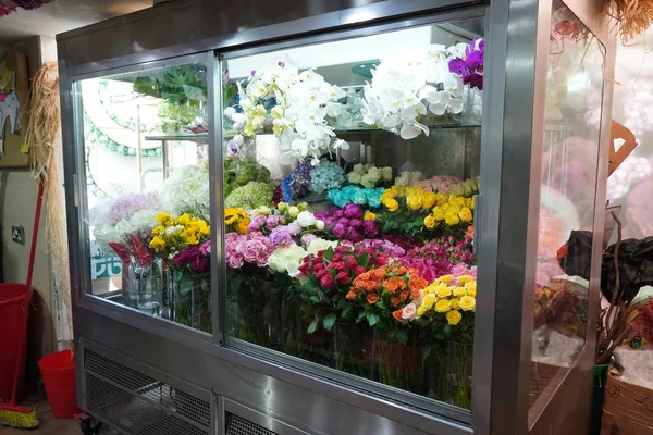 Klimalı özel soğuk bir odada satılık çiçek çeşitleri. Çiçekler için buzdolabı. Buzdolabının önünde gül, şakayık, lale gibi çiçek buketleri var.. — Stok fotoğraf