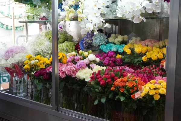 Variedade de flores à venda em uma sala de frio especial com ar condicionado. Frigorífico para flores. Frente de geladeira com buquês de flores como rosas, peônia, tulipas em uma loja florista em um shopping. — Fotografia de Stock