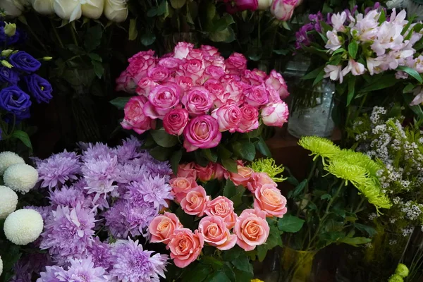 Renkli güller ve diğer farklı çiçeklerle dolu buket. Çiftçi pazarındaki çiçekçi dükkanının girişinde. Renkli şakayık, güller vesaire. Çiçekçi dükkanının rafında saksılar. Dubai BAE Aralık 2019 — Stok fotoğraf
