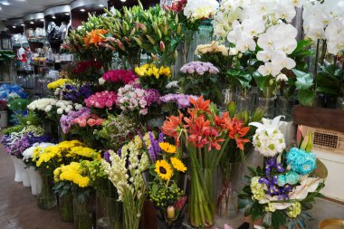 Renkli güller ve diğer farklı çiçeklerle dolu buket. Çiftçi pazarındaki çiçekçi dükkanının girişinde. Renkli şakayık, güller vesaire. Çiçekçi dükkanının rafında saksılar. Dubai BAE Aralık 2019