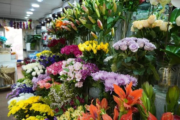 Renkli güller ve diğer farklı çiçeklerle dolu buket. Çiftçi pazarındaki çiçekçi dükkanının girişinde. Renkli şakayık, güller vesaire. Çiçekçi dükkanının rafında saksılar. Dubai BAE Aralık 2019 — Stok fotoğraf