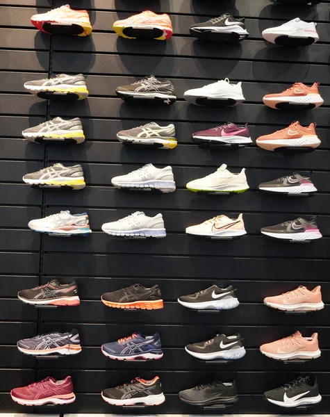 Tienda de exhibicion de una gran cantidad de zapatos deportivos en una pared. Una vista de una pared de zapatos dentro de la tienda. Zapatillas de deporte modernas y elegantes para hombres