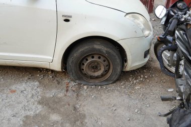 Tire leak, close up wheel of old white vintage car. Car wheel flat tire on the road. Deflated the tyre of an old car next to a motorcycle. - Udaipur India : February 2020