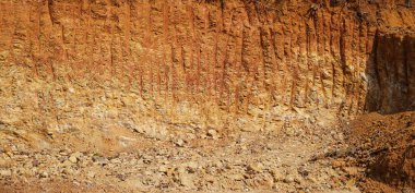 Ormanların kökleriyle yok olması, gün ışığında kayaların görünmesi. İnşaat alanında kazıcı kullanarak ormandan toprak çıkarılan kırmızı ve sarı kayalar. Kum kazma kavramı.