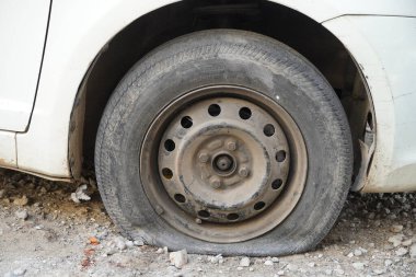 Tire leak, close up wheel of old white vintage car. Car wheel flat tire on the road. Deflated the tyre of an old car next to a motorcycle. - Udaipur India : February 2020