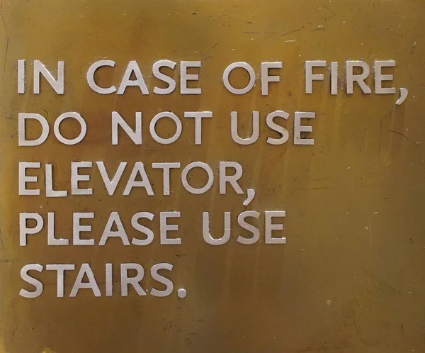 A sign that says, In Case Of Fire, Do Not Use Elevator, Please Use Stairs, which direct people of what to do in case of an fire emergency.