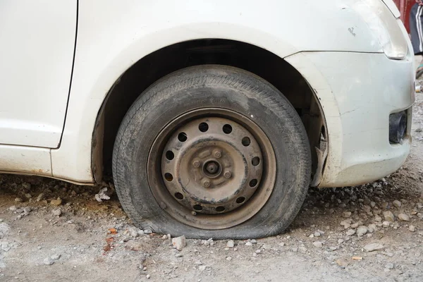 Tire leak, close up wheel of old white vintage car. Car wheel flat tire on the road. Deflated the tyre of an old car next to a motorcycle. - Udaipur India : February 2020