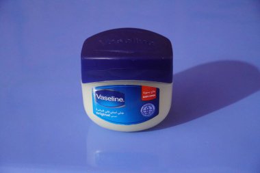 A large tub of Vaseline petroleum jelly isolated blue background. : A jar of Petroleum jelly which is used as over the counter topical ointment. 250 ML : Dubai UAE - March 2020 clipart