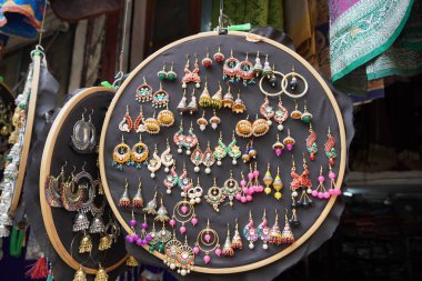 Udaipur Hindistan 'daki sokak pazarında turistler için asılı duran renkli el yapımı küpeler. Sokak pazarında satılık renkli güzel ve şık küpeler..
