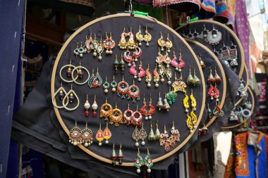 Udaipur Hindistan 'daki sokak pazarında turistler için asılı duran renkli el yapımı küpeler. Sokak pazarında satılık renkli güzel ve şık küpeler..