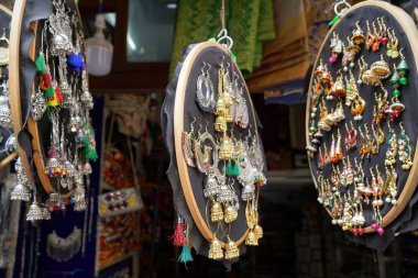 Udaipur Hindistan 'daki sokak pazarında turistler için asılı duran renkli el yapımı küpeler. Sokak pazarında satılık renkli güzel ve şık küpeler..