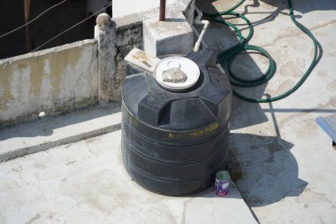 Polivinil klorür PVC su boruları tanımlanamayan bir tanka bağlı. Çatıda ya da güvertede endüstriyel binaların siyah su tankları var. - Mumbai Hindistan: Mayıs 2020