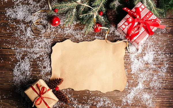 Uma folha limpa de papel de um ramo de uns brinquedos de árvore de Natal de abeto no contexto de madeira escura. Conceito festivo de Natal . — Fotografia de Stock