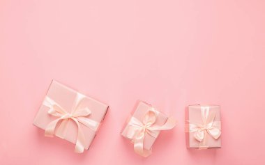 Pastel pembe arka planda saten kurdeleli tatil kutuları. Şen minimalizm konsepti. Düz biçim düzeni.