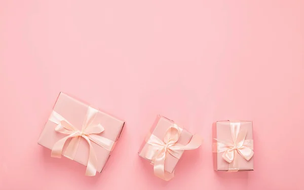 Святкові подарункові коробки з атласною стрічкою на пастельно-рожевому тлі. Святковий концепт мінімалізму. Пласка компонування стилю . — стокове фото