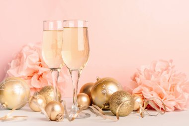 Şampanya cam kadehlerde altın balonlar yıldızlar yılan gibi kıvrılır pastel, pembe arka plan. Yeni yıl şenlik konsepti.