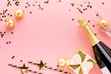 Parlak kağıt, pastel pembe arka planda saten fiyonklu şampanya şişesi hediye eder. Boşluk yeri metin tasarımını kopyala.