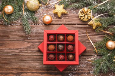 Çikolata şekeri kırmızı el işi kutu ahşap arka planda Noel ağacı dalları Yeni Yıl oyuncağı. Üst görünüm düz düzlem.