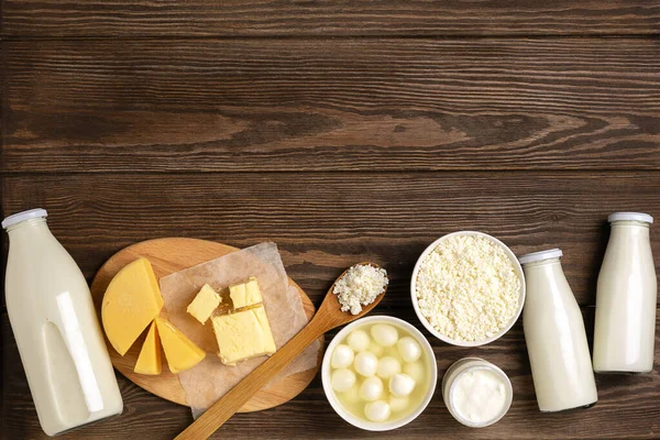 Mléčné kyselé mléčné výrobky na dřevěném tmavém venkovském pozadí. Mléko, kefír, jogurt, máslo, sortiment sýrů. Ploché uspořádání — Stock fotografie