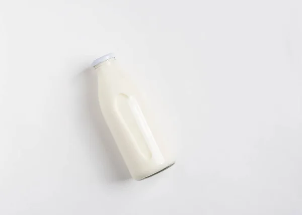 Mléčný nebo bílý mléčný nápoj ve skleněné lahvičce na bílém stole. Zdravý stravovací koncept. Plochý pohled shora. Kopírovat prostor. — Stock fotografie