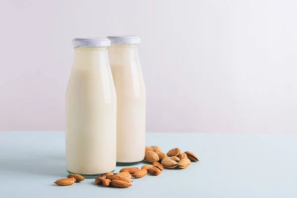 Αμύγδαλο καρύδι γάλα ποτό σε γυάλινα μπουκάλια φως φόντο. Η έννοια της υγιεινής διατροφής. Χώρος αντιγραφής οριζόντιου πλαισίου — Φωτογραφία Αρχείου