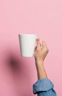 Kadın elinde bir fincan kahve ya da pembe arka plan içeceği tutuyor. Yiyecek içecek konsepti. Uzayı kopyala Dikey çerçeve