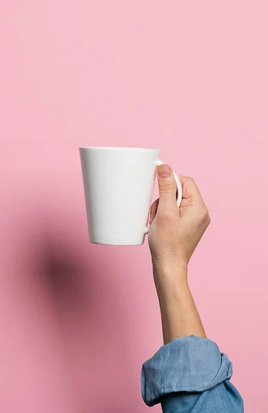 Woman holds in her hands a cup of coffee or tea drink pink background. Food drink concept. Copy space. Vertical frame