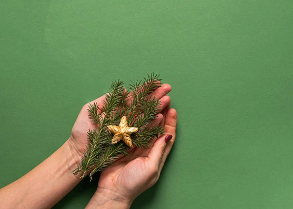 Weihnachtsspielzeugstern aus Naturmaterialien und Tannenzweigen in Frauenhand auf grünem Hintergrund. Weihnachten im Westen — Stockfoto
