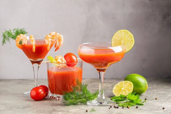 Vari cocktail alcolici da gamberetti succo di pomodoro, sanguinosa Maria e ingredienti pomodoro, lime, gamberetti, sedano. Bevande forti in occhiali eleganti su uno sfondo grigio. Spazio di copia cornice orizzontale . — Foto Stock