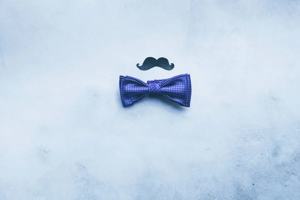 Mens tie butterfly black mustache photo props on a blue fashionable background. Concept of male holiday Flat layout