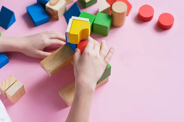 L'enfant recueille le concepteur construit une maison de cubes en bois. Jouets de matériaux naturels environnementaux pour enfants . — Photo