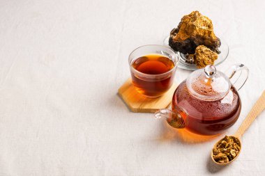 Cam çaydanlık ve bardakta Chaga ağacı mantarından sağIık çayı. Organik içecek antioksidan gri doğal arkaplan.