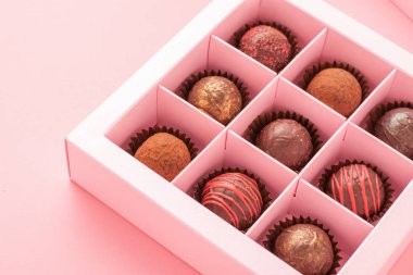 Kutu pembe arka planda çikolatalı trüf şekerleri. Bayramlık yemek aşkı konsepti. Yatay çerçeve kopyalama alanı .