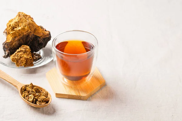 Curación de té de champiñones de abedul chaga en una taza de vidrio. Bebida orgánica antioxidante. El concepto de nutrición saludable — Foto de Stock