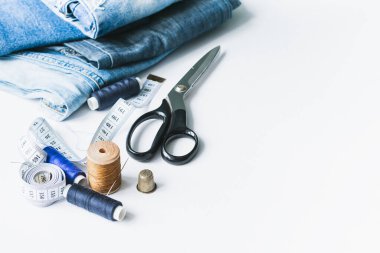 El işi, giysi tamiri. Beyaz arka planda kumaş kotlar ve dikiş aksesuarları. Ekonomik şeyler kavramı