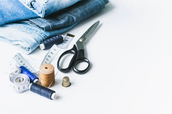 Handicraft, clothing repair. Cloth denim and sewing accessories on a white background. The concept of economical things