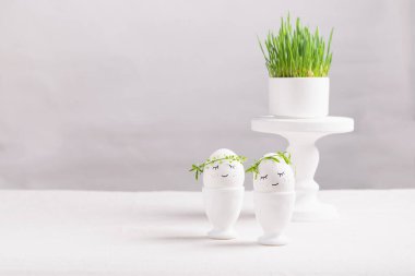 Kutlama kompozisyonu, fincanlarda Paskalya yumurtası ve beyaz bir masada yeşil bitki lahanası. Hafif arkaplan Mutlu Paskalya kavramı.