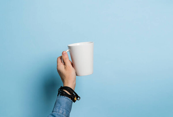 Woman holds in her hands a cup of coffee or tea drink pink background. Food drink concept. Copy space. Horizontal frame