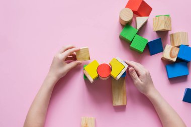 The child collects the designer builds a house of wooden cubes. Toys from environmental natural materials for children.