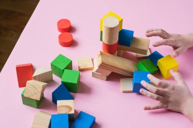 The child collects the designer builds a house of wooden cubes. Toys from environmental natural materials for children.